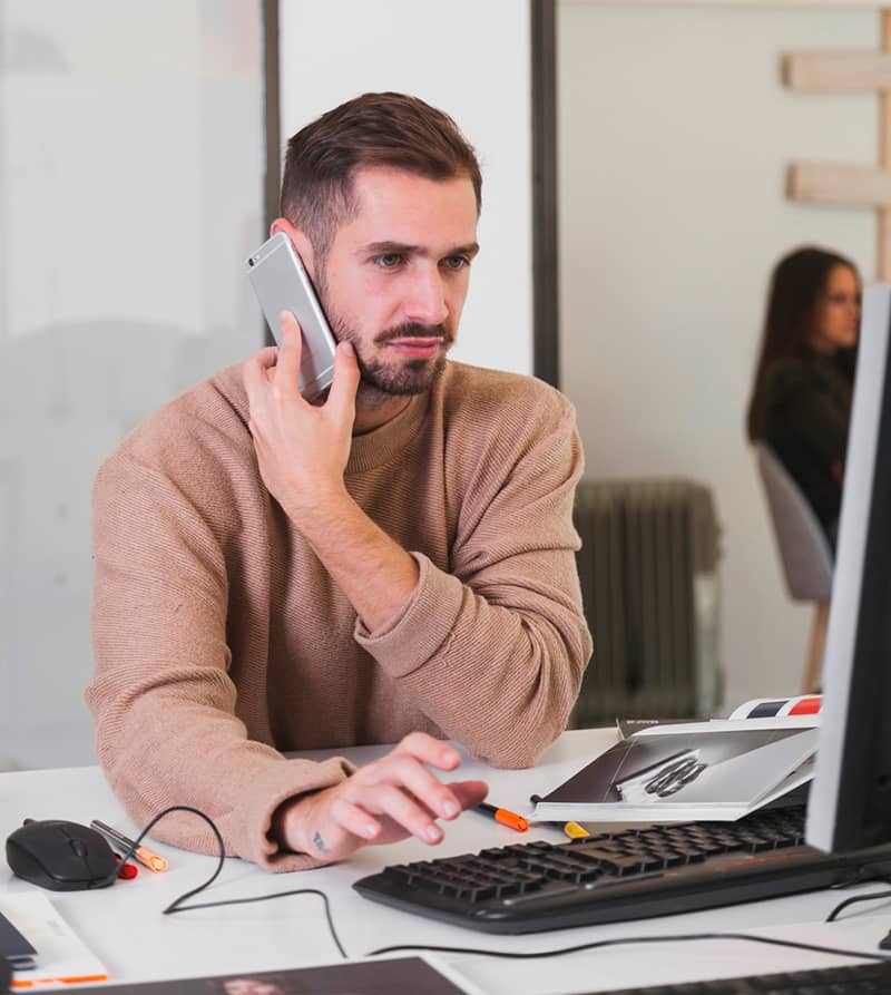 Photo d'un homme parlant au téléphone devant un ordinateur